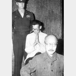 東京裁判初公判で精神錯乱状態となり、祈りのポーズをとる大川周明。この前後に前に座る東條英機の頭をたたく奇行に出たという＝1946年5月3日（Ｃ）共同通信社